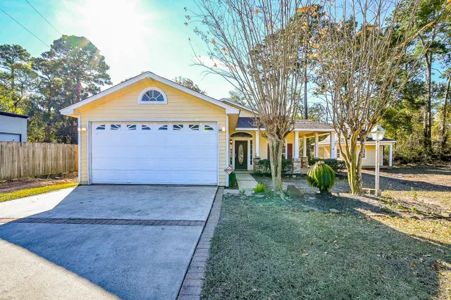 a view of a house with a yard and a large tree