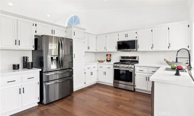 a kitchen with cabinets stainless steel appliances and wooden floor