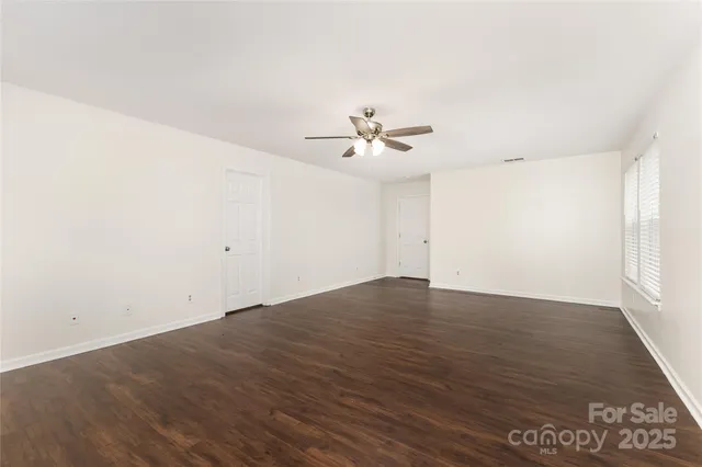 an empty room with wooden floor and fan