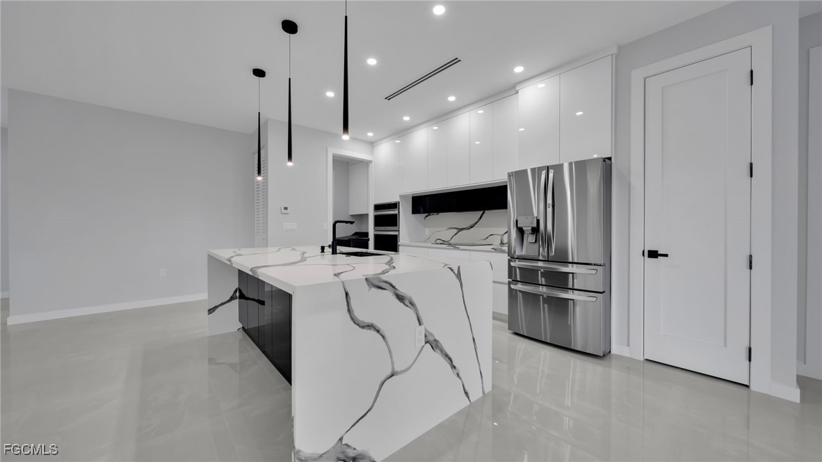 910 Northwest 36th Place Cape Coral, FL 33993 - Photo 11 of 46 a kitchen with a refrigerator a stove and kitchen island