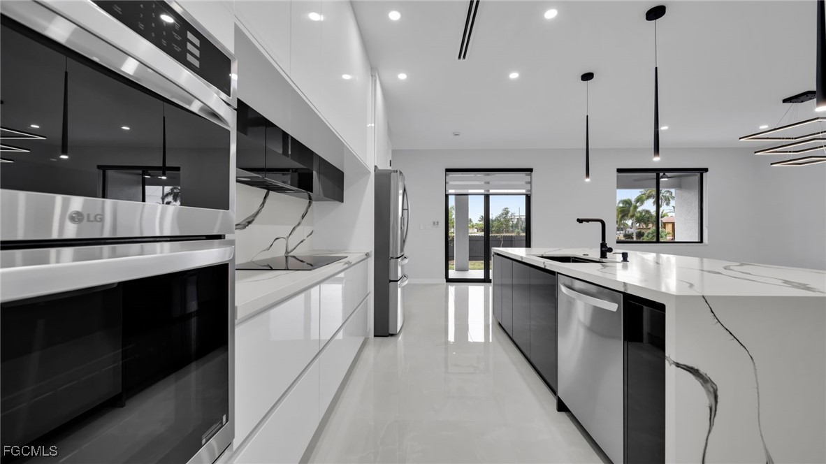 910 Northwest 36th Place Cape Coral, FL 33993 - Photo 14 of 46 a large kitchen with stainless steel appliances kitchen island a large counter space a sink and cabinets