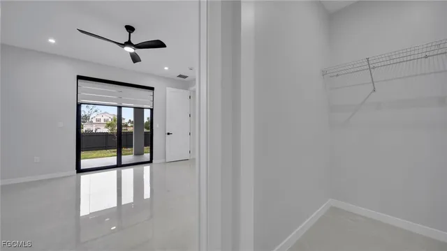 a view of hallway with window and a ceiling fan