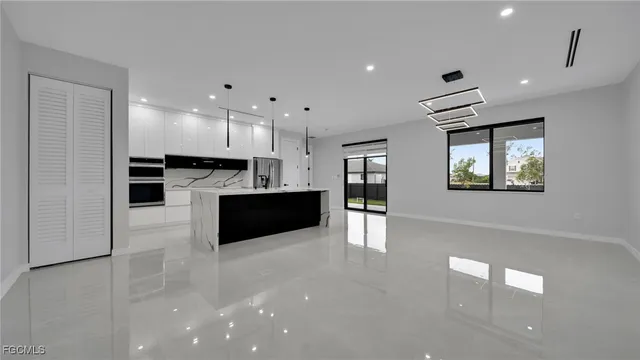 a large white kitchen with kitchen island a sink wooden floor and a stove top oven