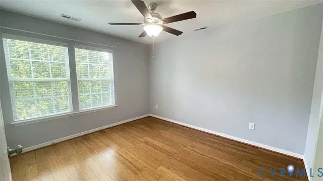 a view of an empty room with a window and a ceiling fan