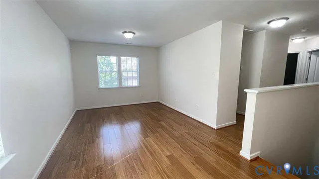 an empty room with wooden floor and window