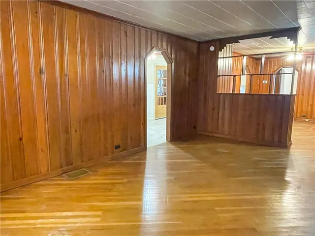 a view of an empty room with wooden floor and windows