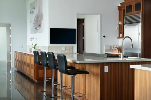 a kitchen with stainless steel appliances granite countertop a table chairs in it and a flat screen tv
