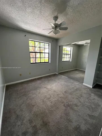 en empty room with windows and chandelier fan