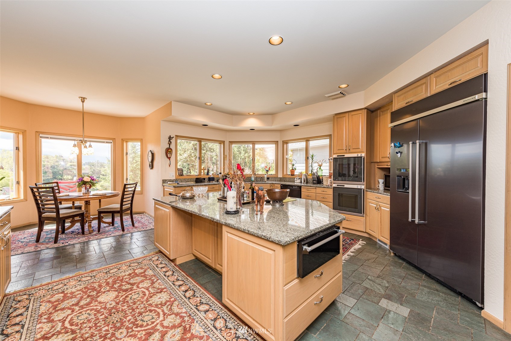 4949 Woodcock Road Sequim, WA 98382 - Photo 14 of 40 a kitchen with stainless steel appliances granite countertop a stove refrigerator and a dining table with wooden floor