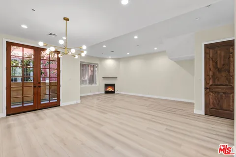 a view of an empty room with wooden floor fireplace and a window