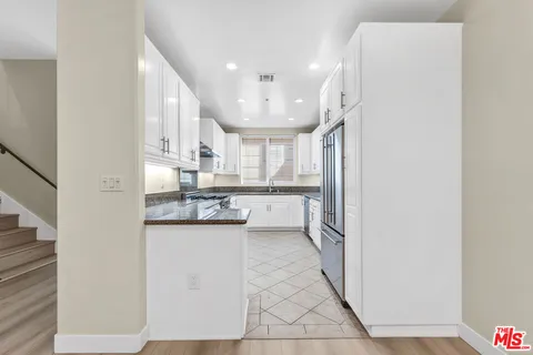 a kitchen with granite countertop white cabinets and white appliances