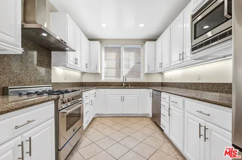 a kitchen with granite countertop white cabinets stainless steel appliances and a sink
