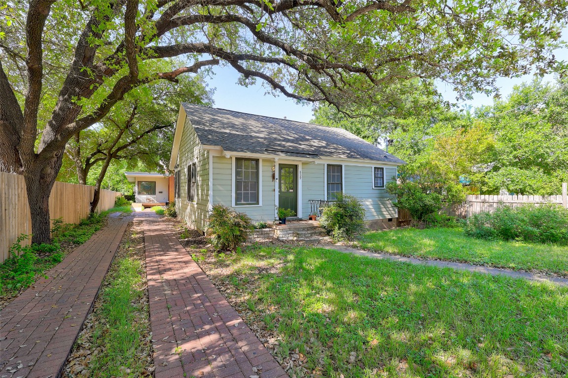 Bungalow-style house with a shingled roof, a front lawn, and fence