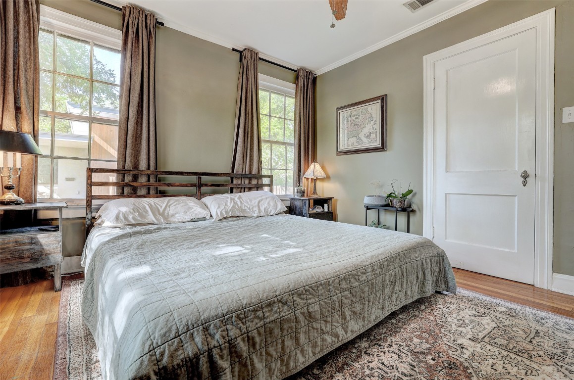 809 East 44th Street Austin, TX 78751 - Photo 16 of 40 Bedroom featuring wood finished floors, visible vents, ceiling fan, and ornamental molding