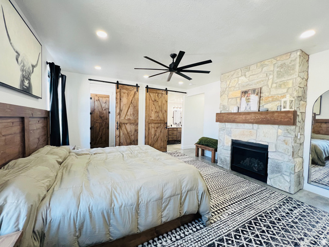 100 Whit Lane Georgetown, ID 83239 - Photo 26 of 76 Bedroom with a barn door, a ceiling fan, a fireplace, and ensuite bath