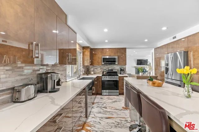a kitchen with stainless steel appliances kitchen island granite countertop a refrigerator and cabinets