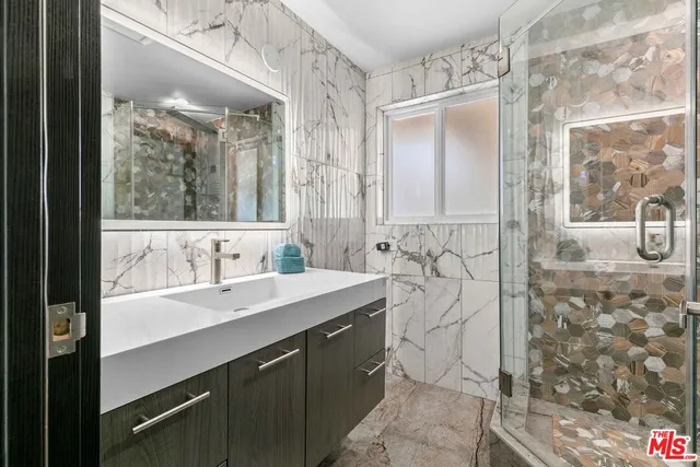 a bathroom with a granite countertop sink mirror and shower