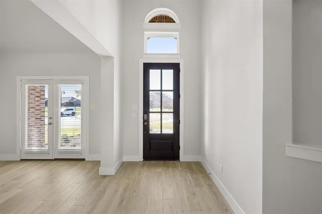 an empty room with wooden floor cabinet and windows