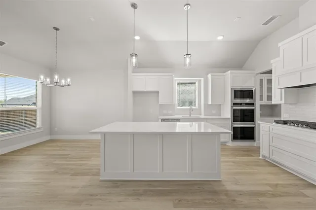 a large kitchen with kitchen island a stove a sink a center island and wooden floor