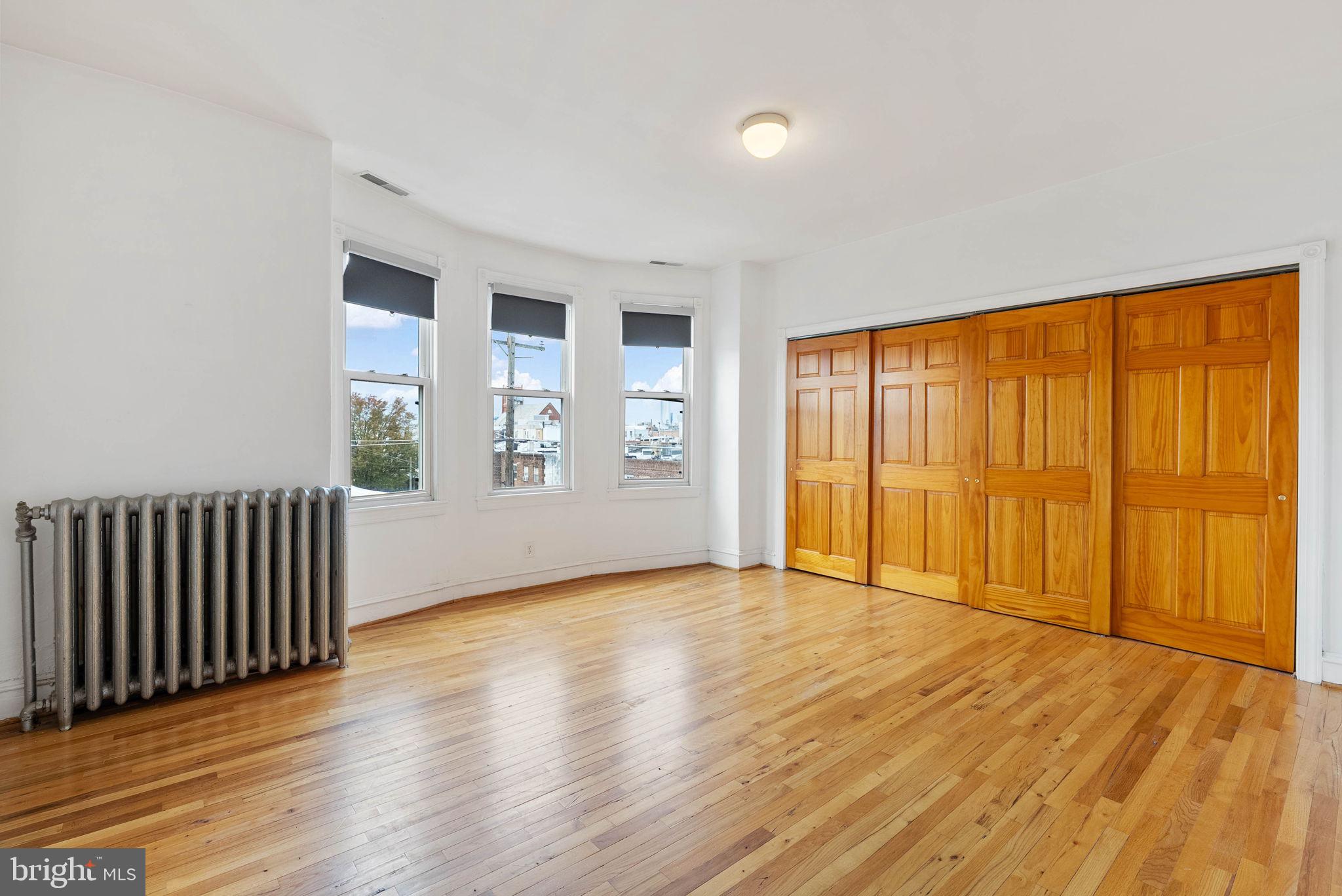 732 Tasker Street, Unit 3 Philadelphia, PA 19148 - Photo 5 of 9 an empty room with wooden floor and windows