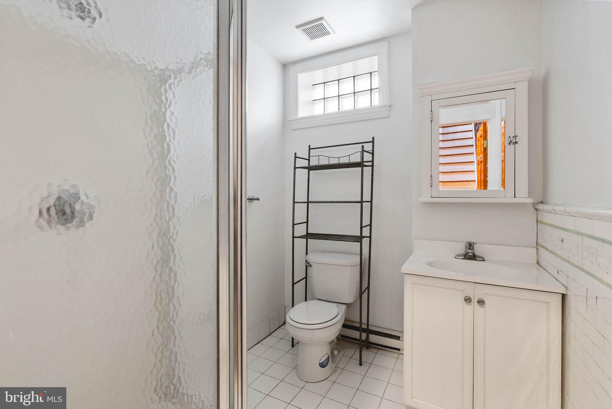732 Tasker Street, Unit 3 Philadelphia, PA 19148 - Photo 6 of 9 a bathroom with a toilet sink vanity and mirror
