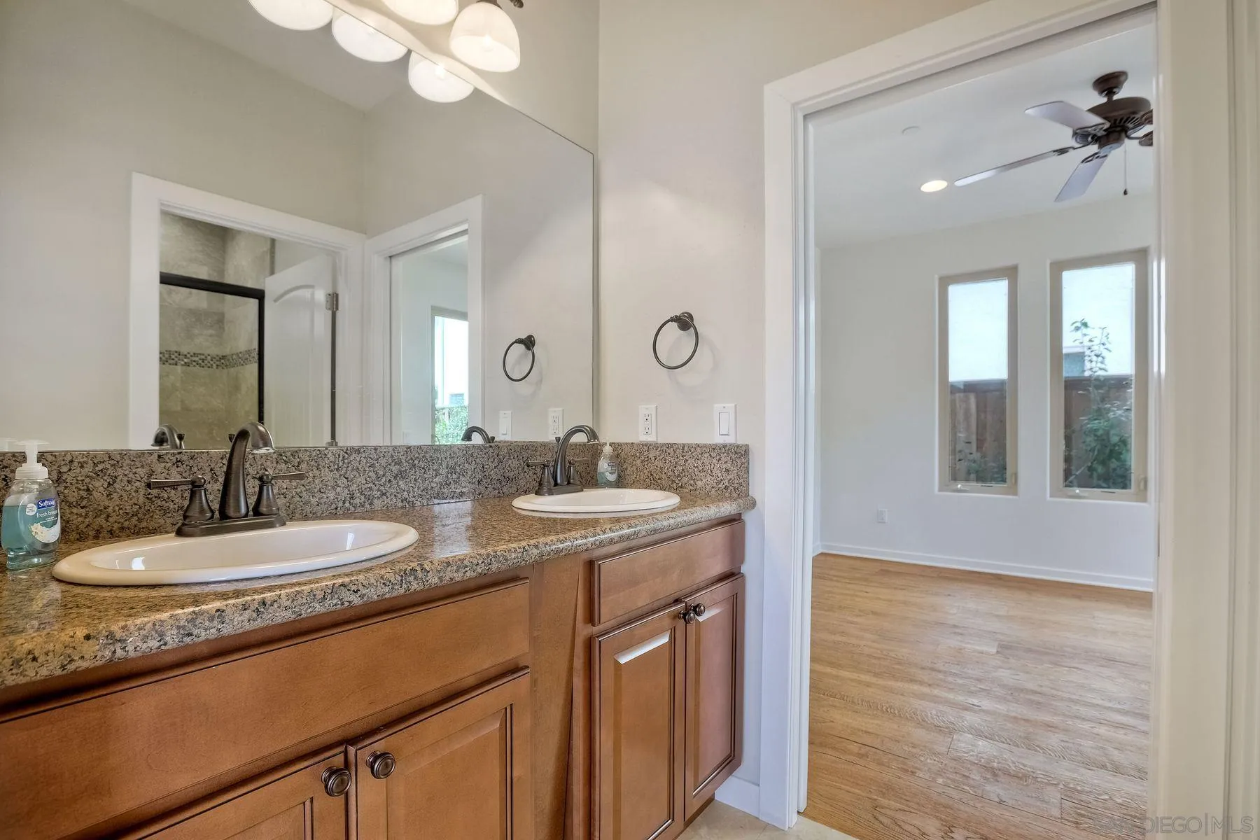 2009 MacKinnon Avenue Encinitas, CA 92007 - Photo 22 of 46 a bathroom with a granite countertop sink a large mirror and a shower