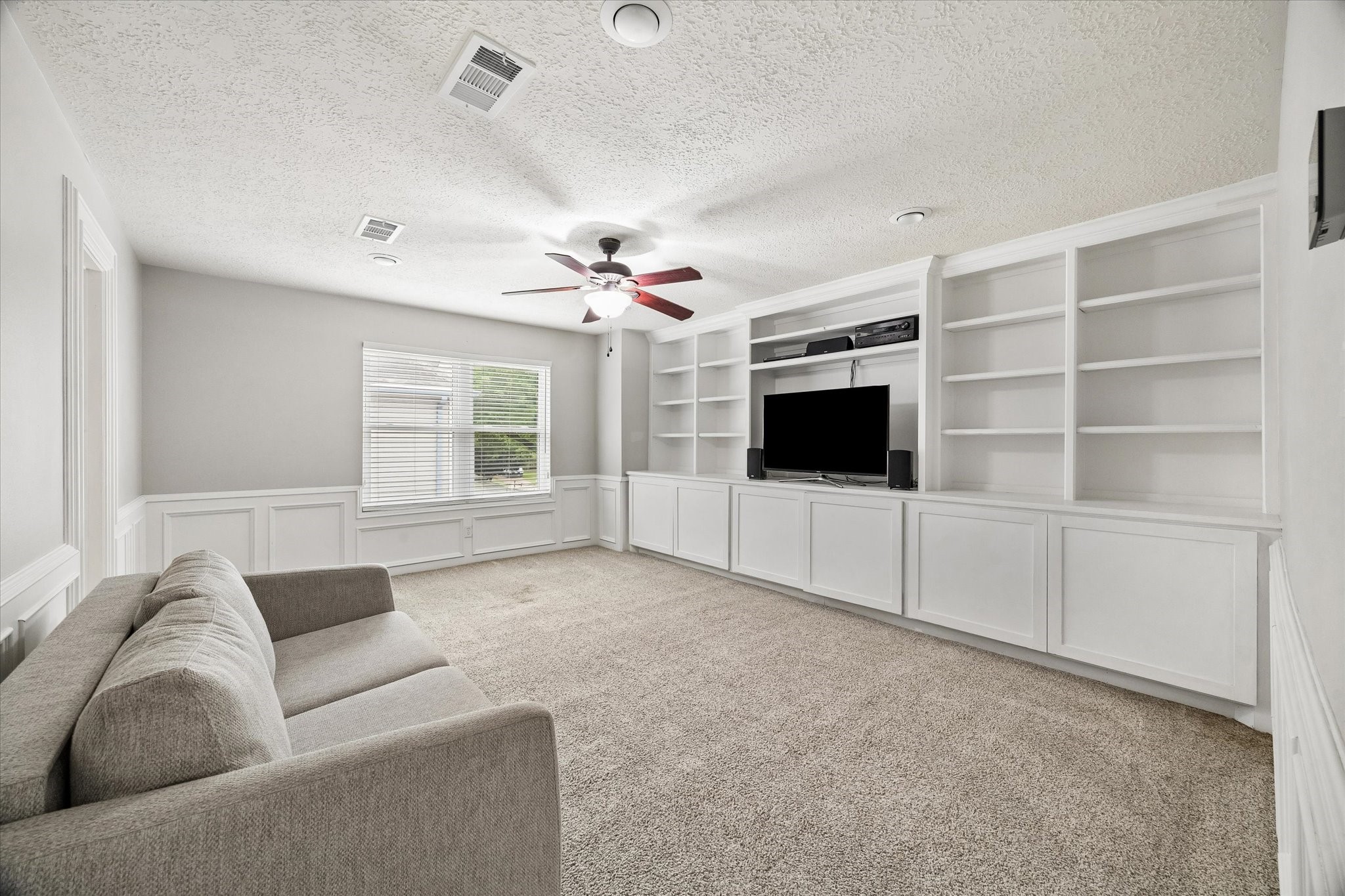 9410 Taidswood Drive Spring, TX 77379 - Photo 36 of 40 The upstairs game room is LARGE and has an entire wall of beautiful wood built in cabinets! This is the perfect space for teens to hang out, have a workout room, a giant play room, or another home office. The possibilities are endless here! A window faces out to the side yard allowing beautiful natural light to fill this space and of course, a ceiling fan is here to keep this room feeling great all the time!