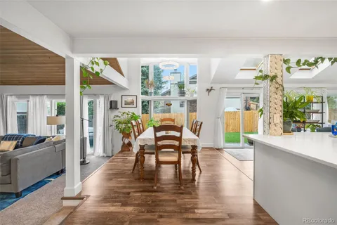 a kitchen with stainless steel appliances granite countertop a dining table chairs and wooden floor