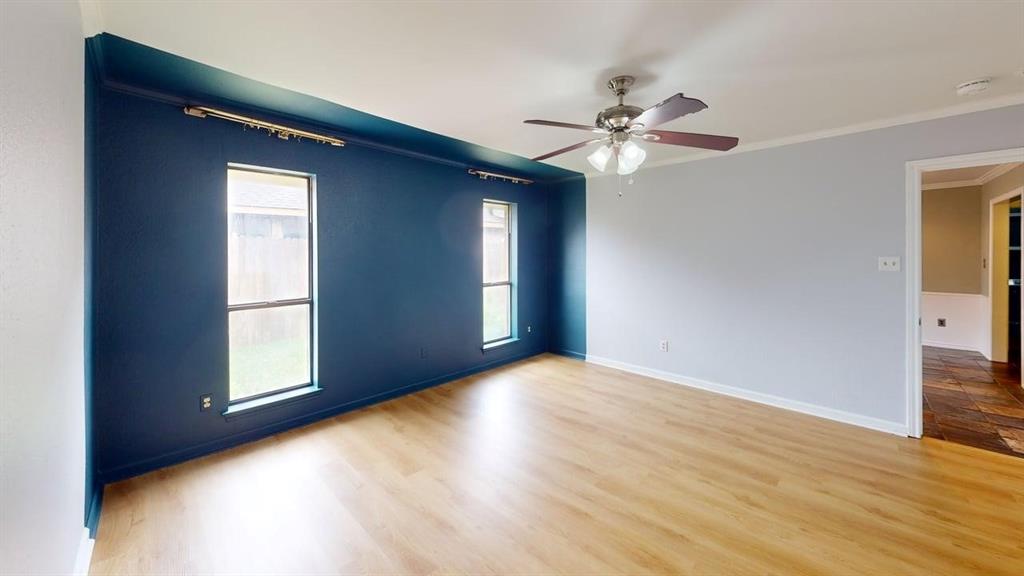 1535 Raleigh Drive Carrollton, TX 75007 - Photo 12 of 24 Spacious interior room featuring wood-finish flooring, a ceiling fan with integrated lighting, and a distinct accent wall