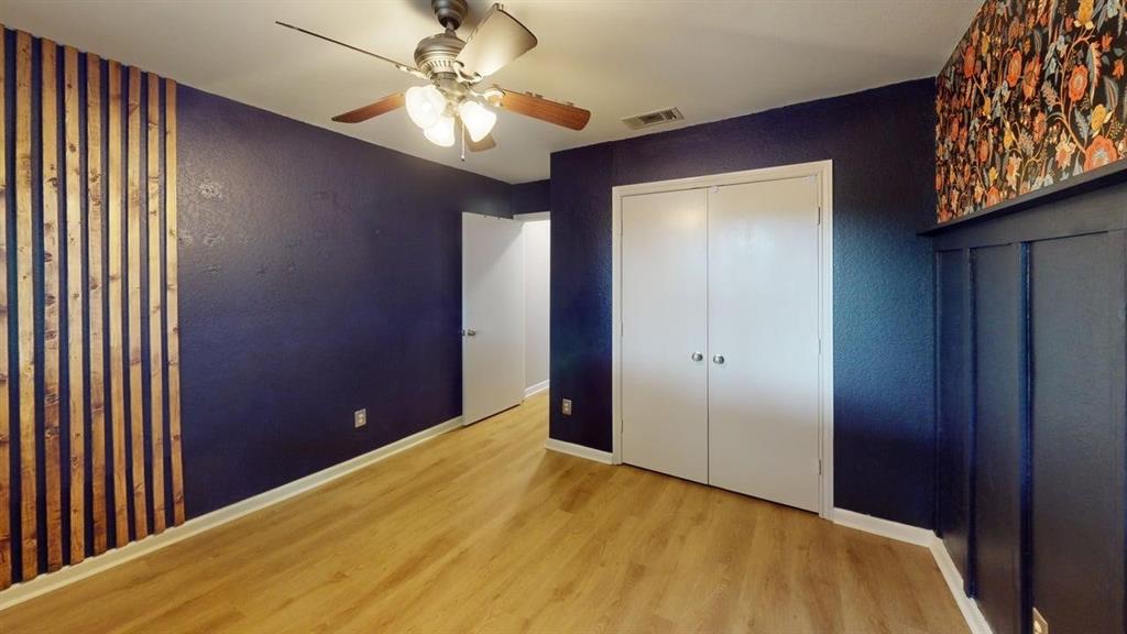 1535 Raleigh Drive Carrollton, TX 75007 - Photo 15 of 24 Room featuring wood-finish flooring, a ceiling fan with light, a wall with vertical wood slat detailing, and a wall with board and batten paneling topped by patterned wallpaper