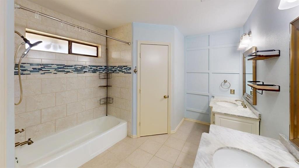 1535 Raleigh Drive Carrollton, TX 75007 - Photo 18 of 24 Bathroom featuring a built-in tub with neutral-toned tile surround and a decorative mosaic accent band