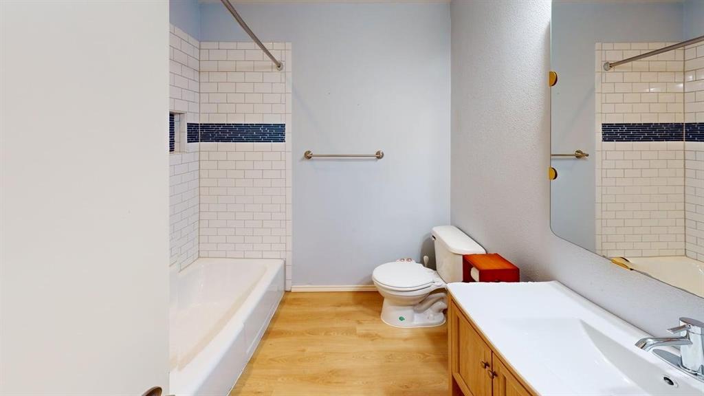 1535 Raleigh Drive Carrollton, TX 75007 - Photo 19 of 24 Bathroom featuring a white subway tile shower surround with a decorative accent band, a built-in shower niche, and a light wood-finish vanity with an integrated sink