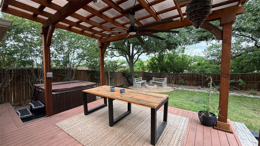 1535 Raleigh Drive Carrollton, TX 75007 - Photo 20 of 24 Expansive backyard featuring a stained wood pergola with a translucent roof, a built-in hot tub, and a fire pit area with stone benches