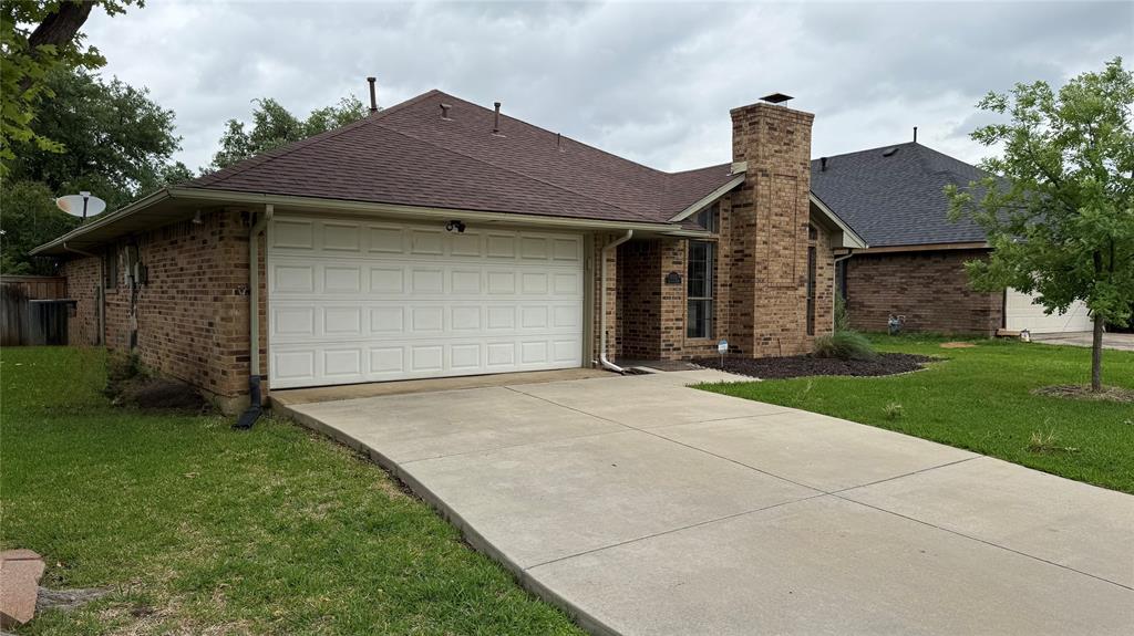 1535 Raleigh Drive Carrollton, TX 75007 - Photo 2 of 24 Brick exterior featuring a two-car garage, concrete driveway, and a prominent brick chimney