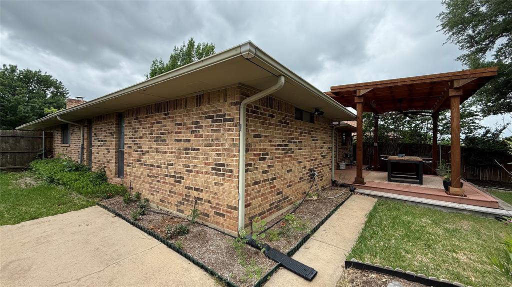 1535 Raleigh Drive Carrollton, TX 75007 - Photo 21 of 24 Brick exterior showcasing a robust wood pergola with a built-in fan, set on a raised deck