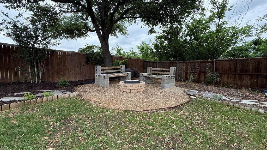 1535 Raleigh Drive Carrollton, TX 75007 - Photo 23 of 24 Backyard fire pit area featuring a gravel base, brick-style fire pit, and two concrete block benches with wood seating