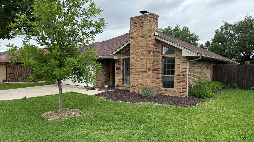 1535 Raleigh Drive Carrollton, TX 75007 - Photo 3 of 24 Brick exterior featuring a prominent chimney, large windows, an attached garage, and a privacy fence