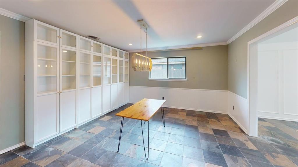 1535 Raleigh Drive Carrollton, TX 75007 - Photo 6 of 24 Spacious room featuring extensive built-in white cabinetry with glass-front uppers and lower storage, complemented by multi-toned slate-look flooring