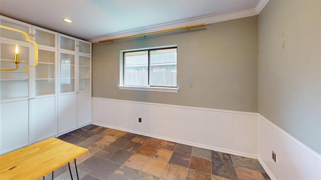 1535 Raleigh Drive Carrollton, TX 75007 - Photo 7 of 24 Built-in white cabinetry with glass display panels, multi-toned stone tile flooring, and a single window with exterior fencing visible