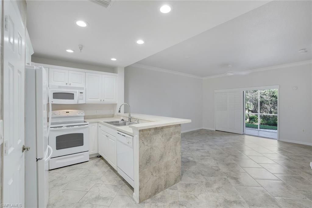 4530 Botanical Pl Circle, Unit 103 Naples, FL 34112 - Photo 11 of 32 Kitchen featuring sink, white appliances, ornamental molding, white cabinets, and kitchen peninsula