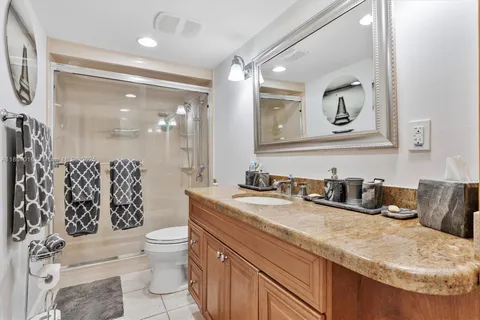 a bathroom with a granite countertop sink mirror vanity and toilet