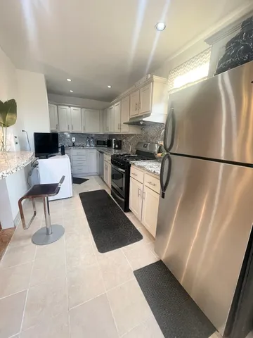 a kitchen with a stove a sink a refrigerator and chairs