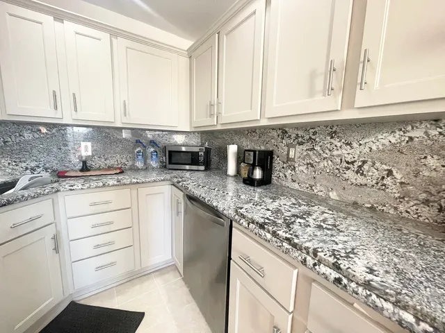 a kitchen with granite countertop white cabinets and stainless steel appliances