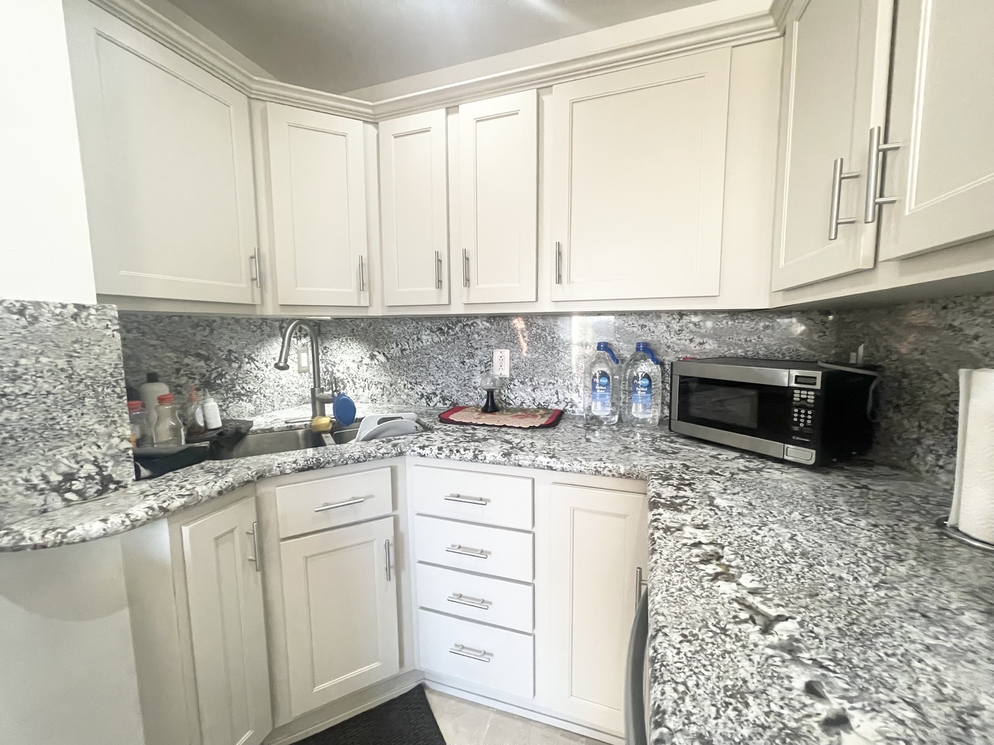2810 West Logan Boulevard, Unit 3W Chicago, IL 60647 - Photo 29 of 34 a kitchen with granite countertop white cabinets and stainless steel appliances