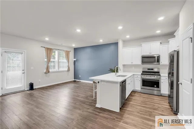 a kitchen with stainless steel appliances a stove top oven a sink a refrigerator cabinets and wooden floor