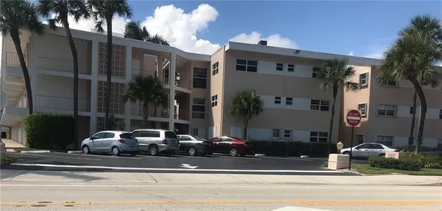 a view of a house with a cars park side of a road