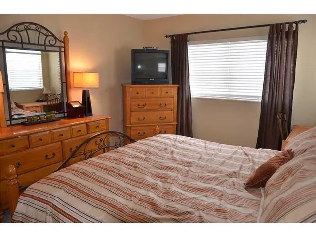 a bedroom with a bed and a flat tv screen on dresser