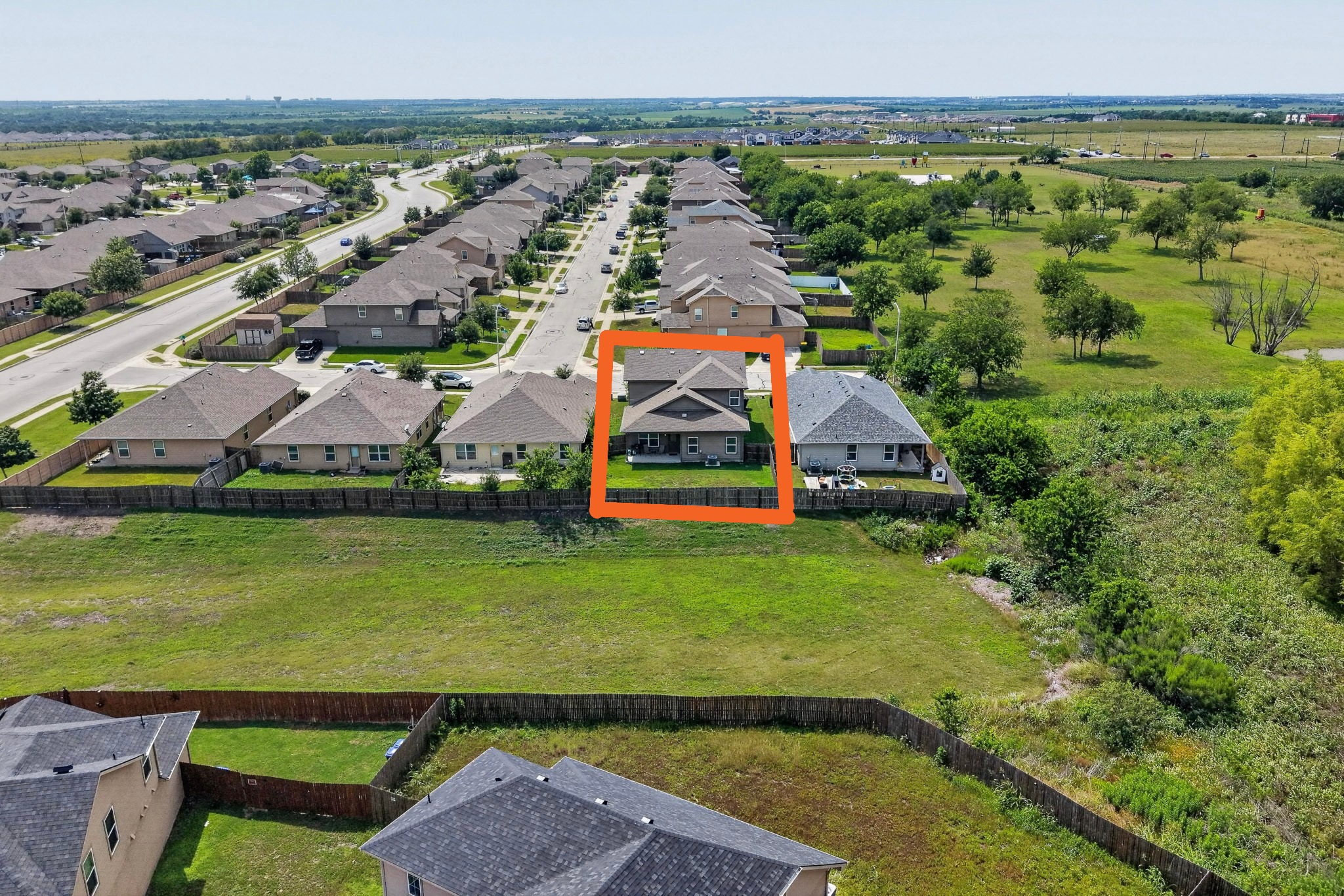 14513 Esker Road Manor, TX 78653 - Photo 36 of 38 An aerial perspective reveals a quiet suburban street, with residences backing onto an undeveloped natural landscape.