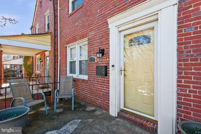 a view of a brick house with a chairs and table in a patio