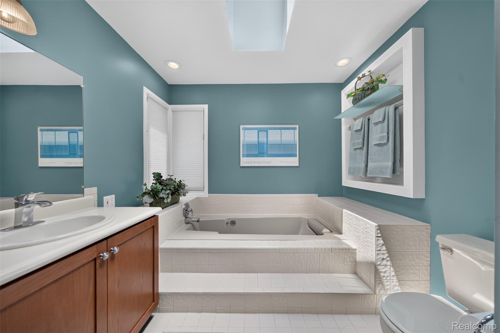 1236 Chaffer Drive Rochester, MI 48306 - Photo 35 of 76 Bathroom featuring a built-in tub with stepped tile surround, a single vanity with wood-finish cabinetry, and a recessed wall niche with glass shelving